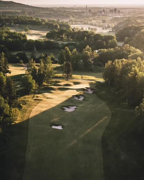 En flygbild av en golfbana omgiven av träd.