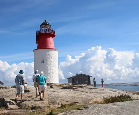 Personer som promenerar mot Hållö fyr.
