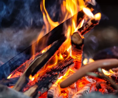 En varmkorv som ligger på en grill bredvid en eld.