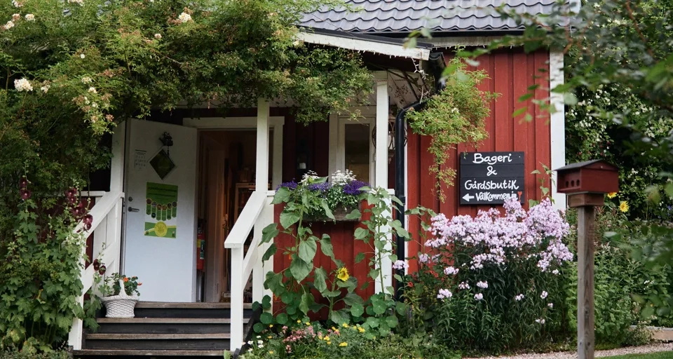 Ett litet rött hus med en vit veranda.