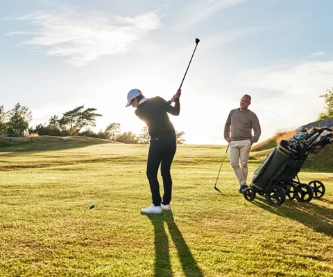 En man och en kvinna som spelar golf en solig dag.