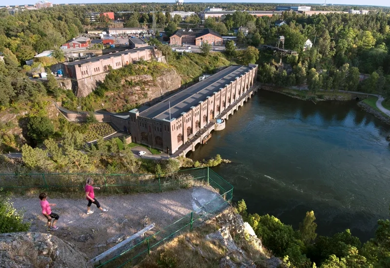 Några människor som går uppför en kulle bredvid en flod.