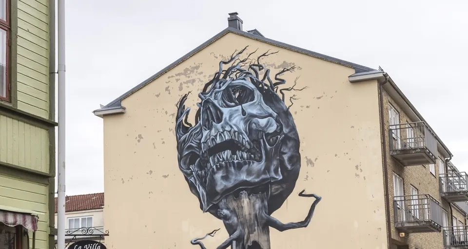 En folkmassa som går längs en gata bredvid höga byggnader.