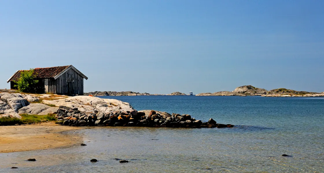 Sjöbod som står på en klippig strand.