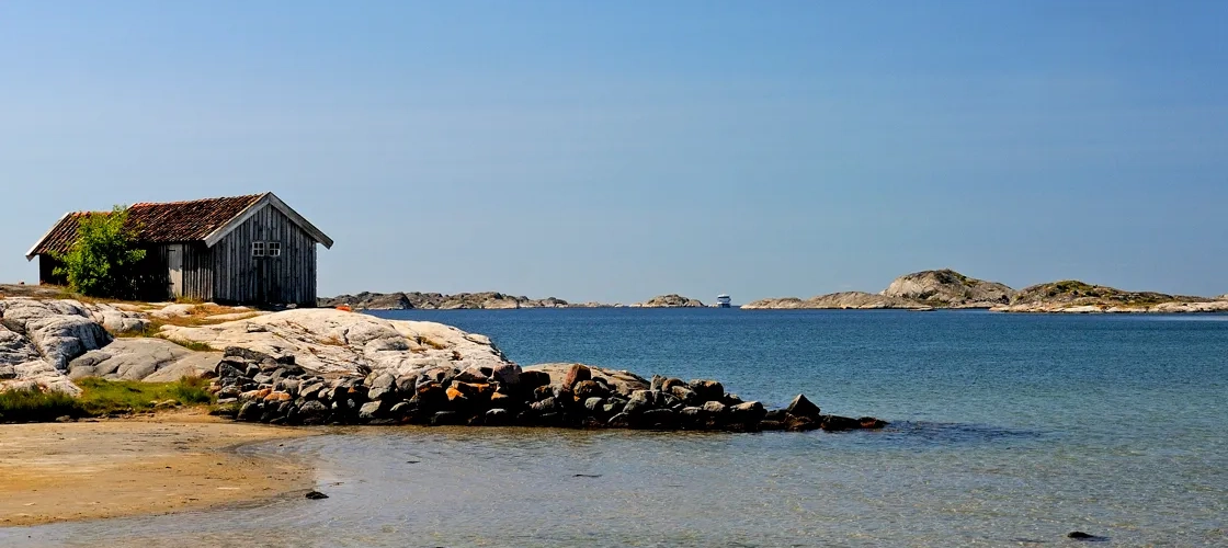 Sjöbod som står på en klippig strand.