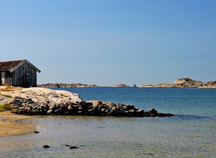 Sjöbod som står på en klippig strand.
