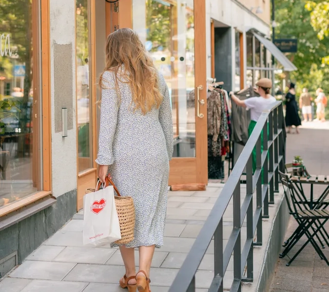 En kvinna syns bakifrån gåendes uppför en ramp till entré till två butiker