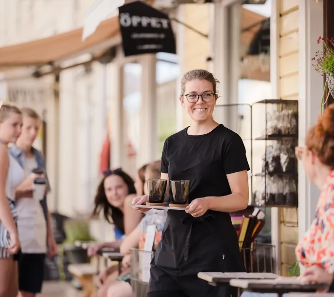 A woman holding a tray of food in front of a group of people.