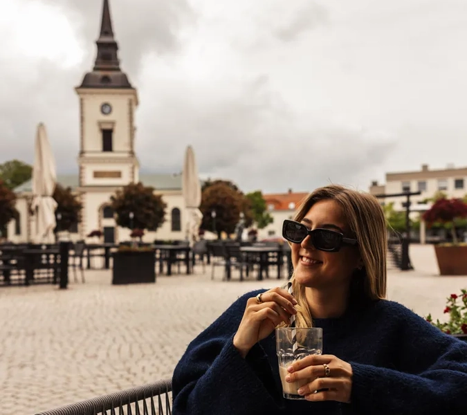 A woman sitting on a bench with a drink in her hand.