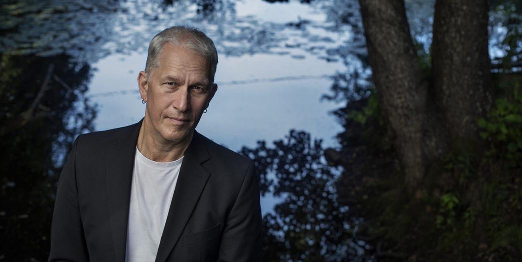 En person som står i en skog med en sjö i bakgrunden.