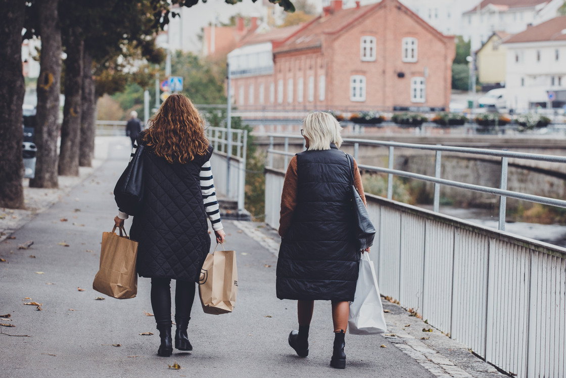 Två kvinnor promenerar med shoppingpåsar i händerna i centrala Strömstad