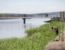 A group of people walking across a bridge over a river.