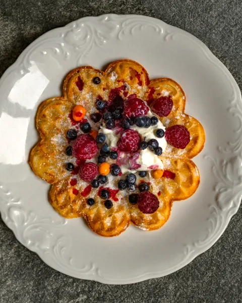 En vit tallrik toppad med våfflor täckta med frukt.