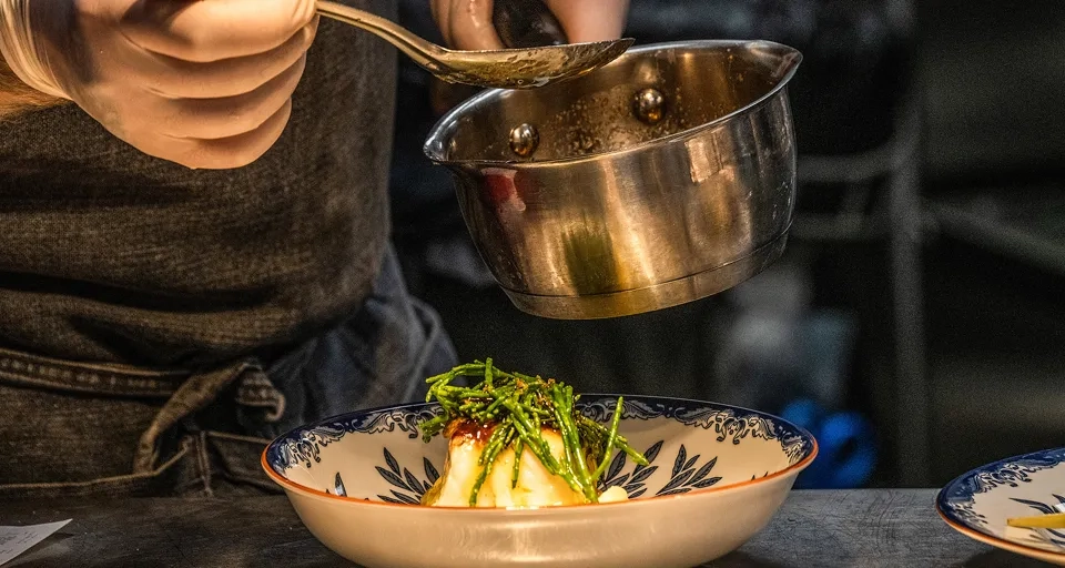 A chef is stirring a dish in a bowl.
