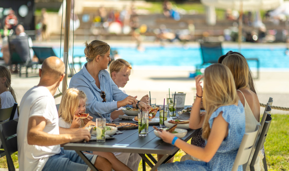 Barnfamilj äter på uteserveringen vid poolen på Tjörnbro Arena