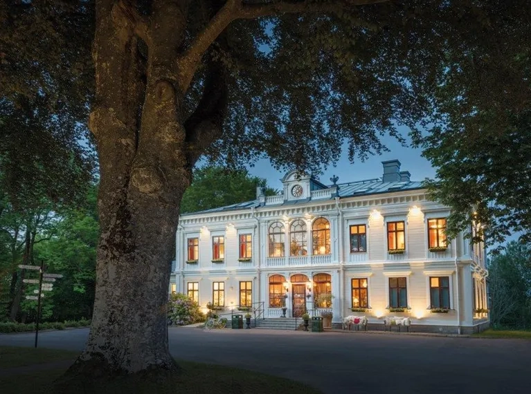 En stor gul byggnad där lampornas sken från fönstren lyser upp i mörkret.