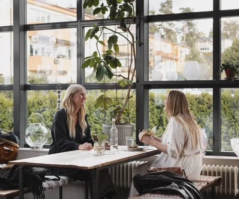Två kvinnor sitter vid ett bord och pratar med varandra.