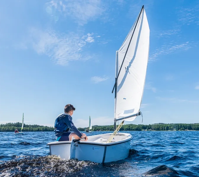 En man på en segelbåt på toppen av ett vattendrag.