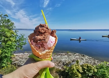 En person som håller upp en glass framför ett vattendrag.