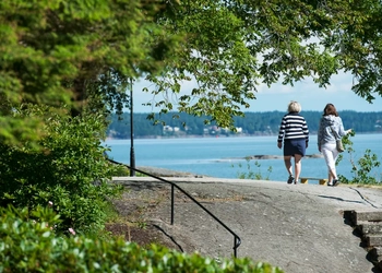 Två personer promenerar vid Vänerns vatten