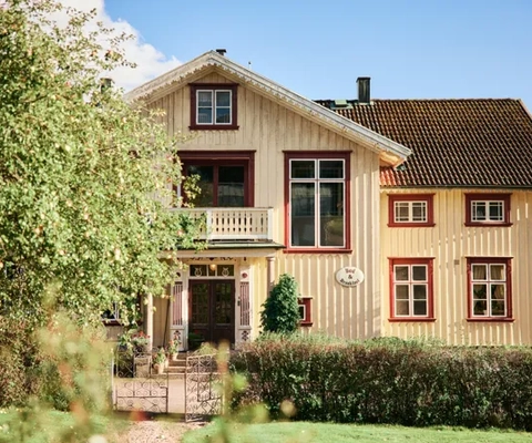 Ett gult hus med brunt tak och röda lister.