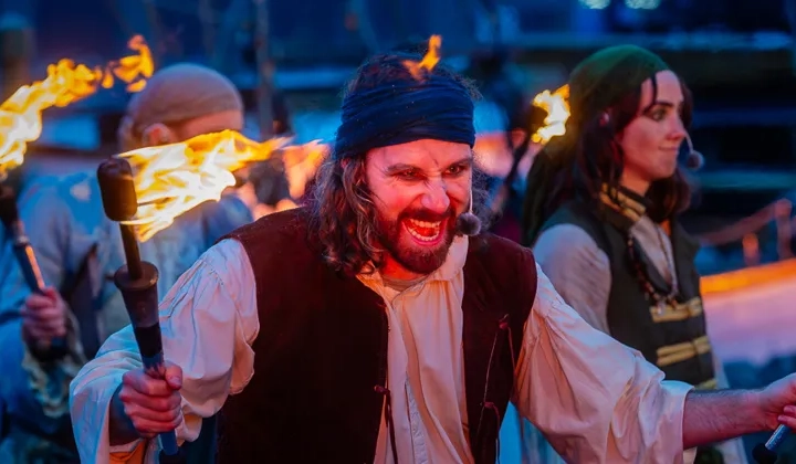 En man i piratdräkt som håller facklor.