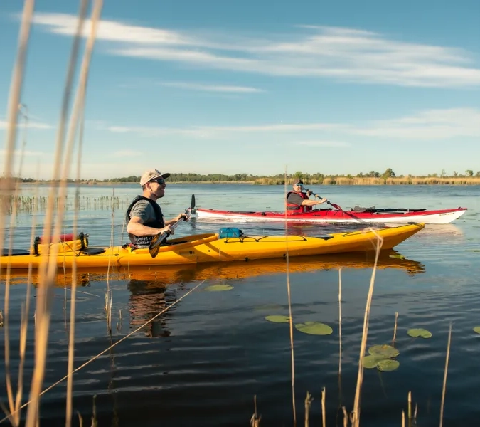 Två personer paddlar kajak på en sjö.