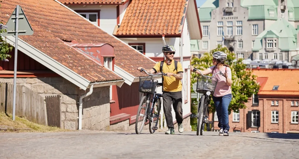 Två personer cyklar i en småstad.