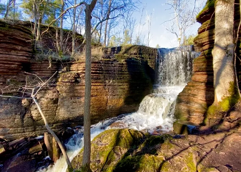 En liten vattenfall där vattnet rinner ner en vacker vårdag vid Martorpsfallet på Kinnekulle.