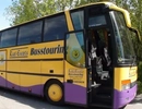 En gul och lila buss parkerad vid sidan av vägen.