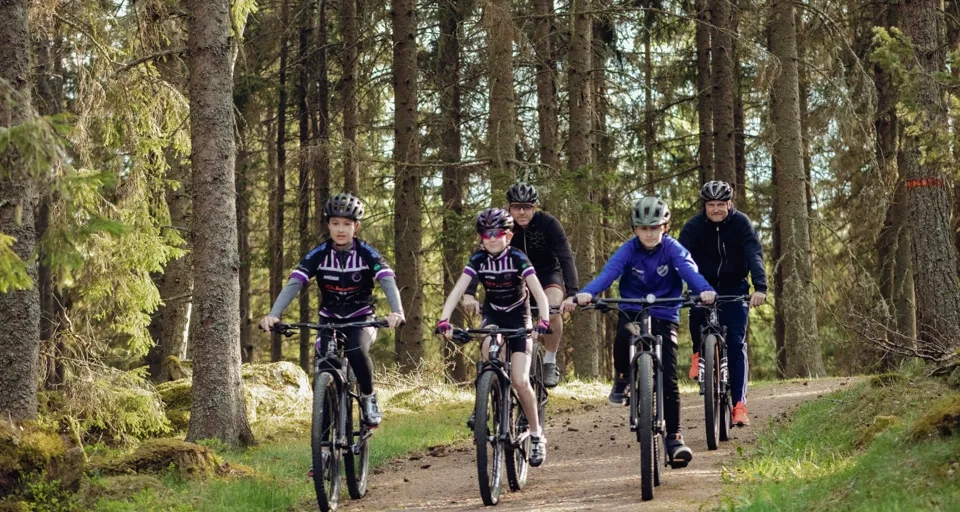 Eine Gruppe von Leuten, die auf Fahrrädern eine unbefestigte Straße hinunterfahren.