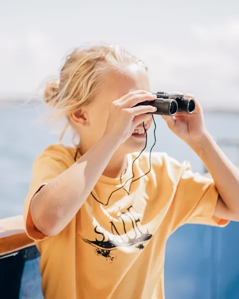 Barn tittar i kikare ut över havet.