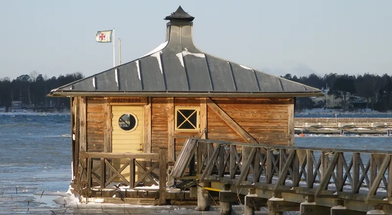 En liten träbyggnad som flyter på en sjö.