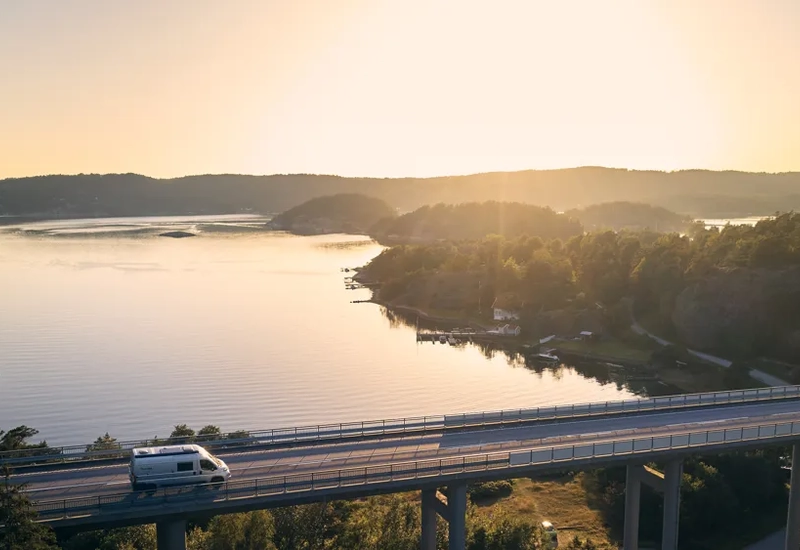 A car driving on a bridge over a lake.