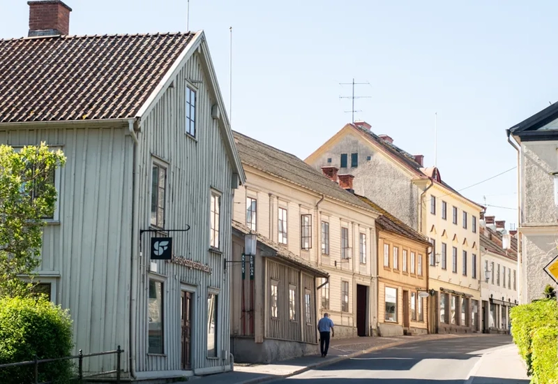 En tom gata med en person som går, gamla hus runt omkring i trä