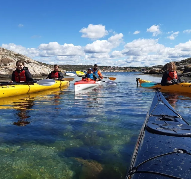 En gruppe mennesker som rir kajakk på toppen av en vannmasse.