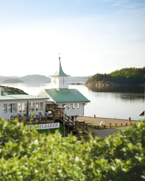 En vit byggnad med ett grönt tak intill ett vattendrag.