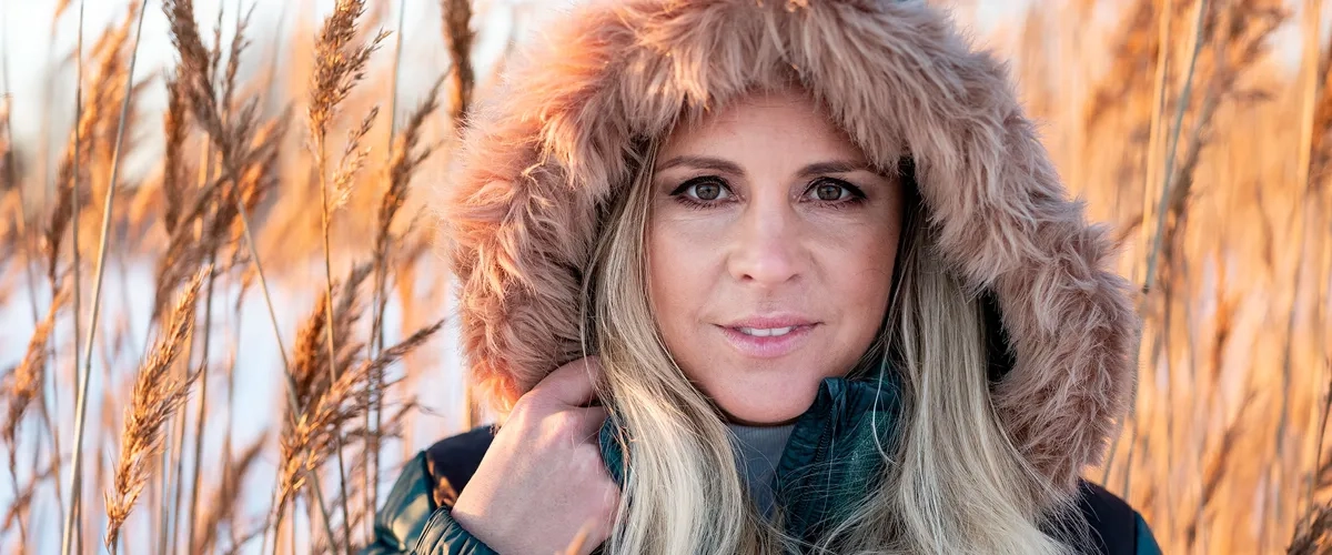 En kvinna med långt blont hår som bär en pälsmössa.