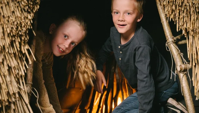 Två barn som kikar ut ur en koja av vass.