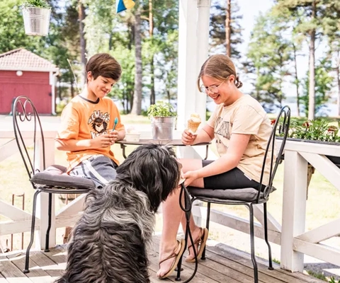 Barn äter glass med en hund vid sidan av bordet.