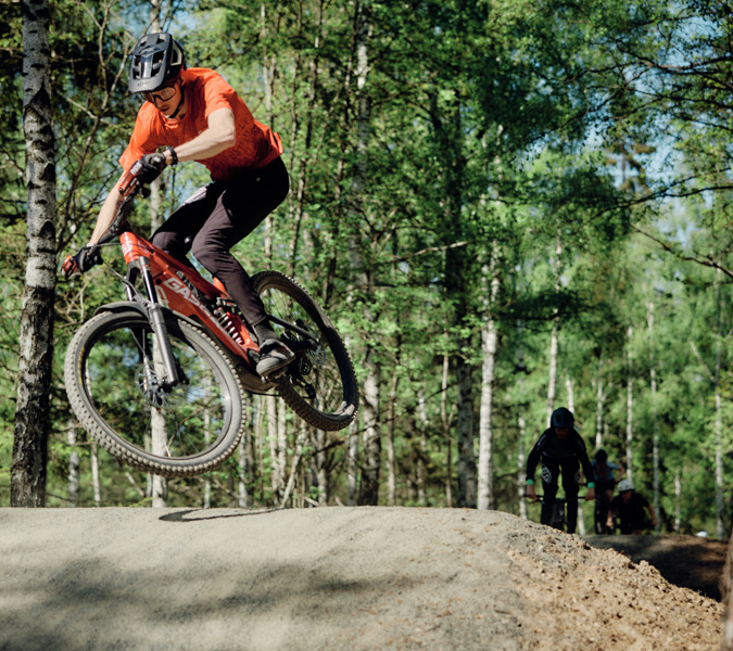 En man cyklar över en grusbacke.