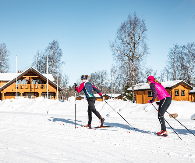 Två längdskidåkare åker jämte Billingens stugby & camping.