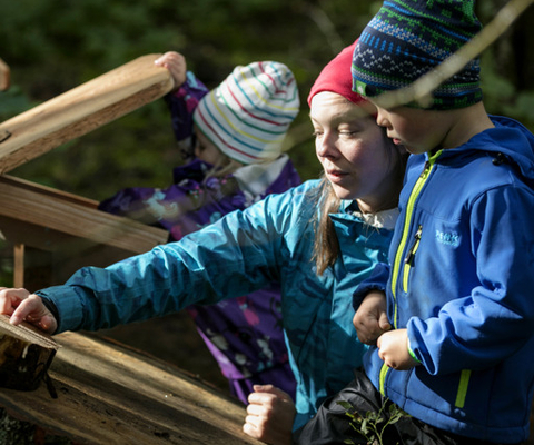 Några barn och kvinna som står bredvid varandra i skogen.