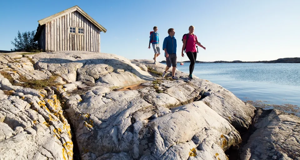 Sällskap vandrar på klipporna vid sjöbod ute på Sydkoster.