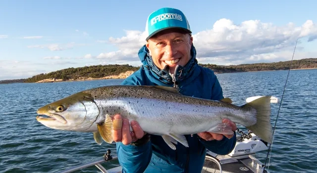 bild på en man som håller en havsöring ute på havet och är glad