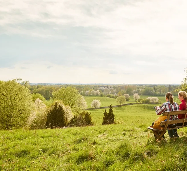 Två personer sitter på en bänk på en ås.