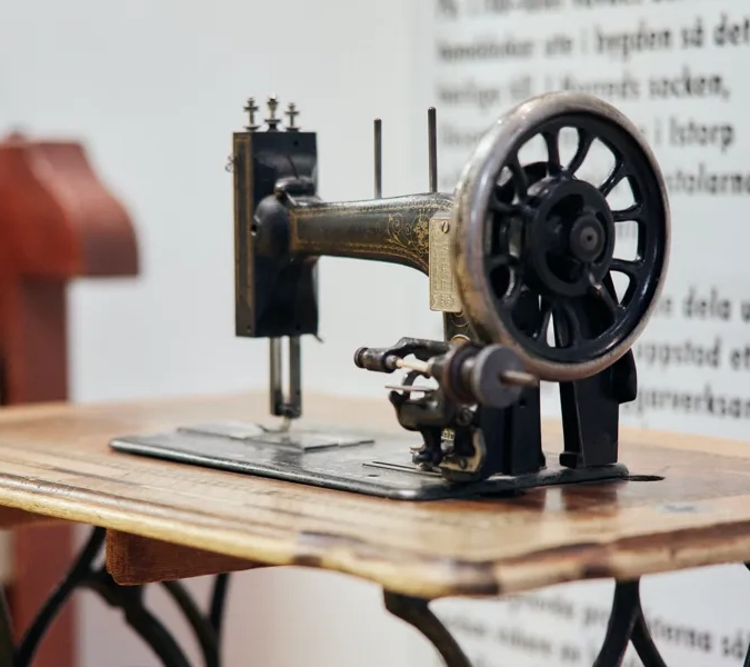 En symaskin som sitter på ett träbord.