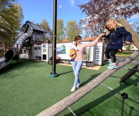 En kvinna och en ung flicka leker på en lekplats.