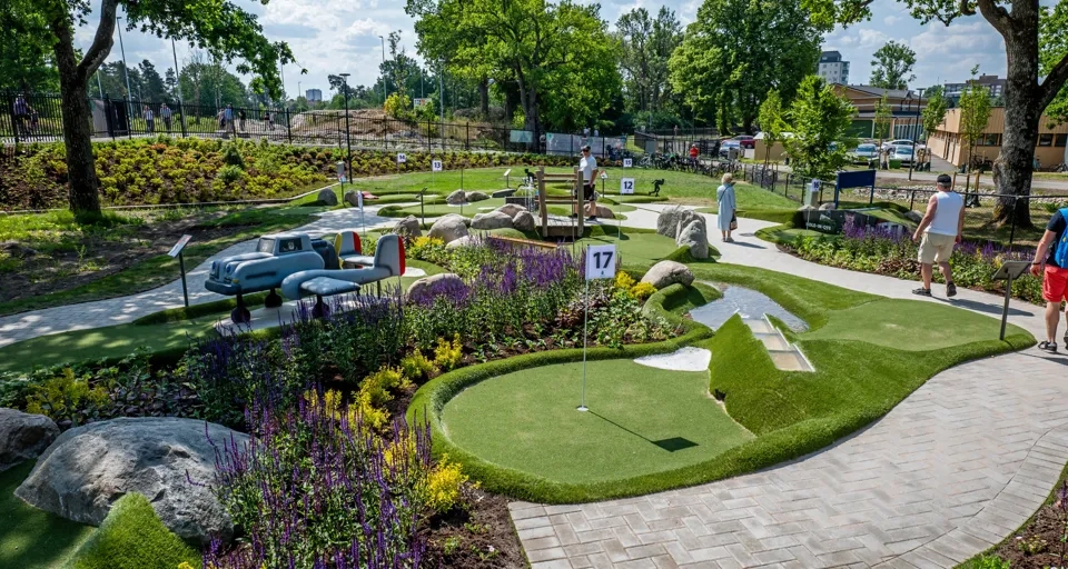 En man går längs en stig intill en grönskande park.