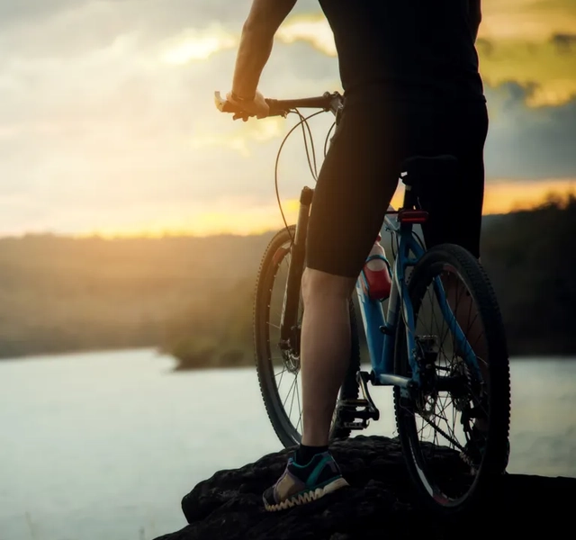 Person som står på en cykel med utsikt över en sjö